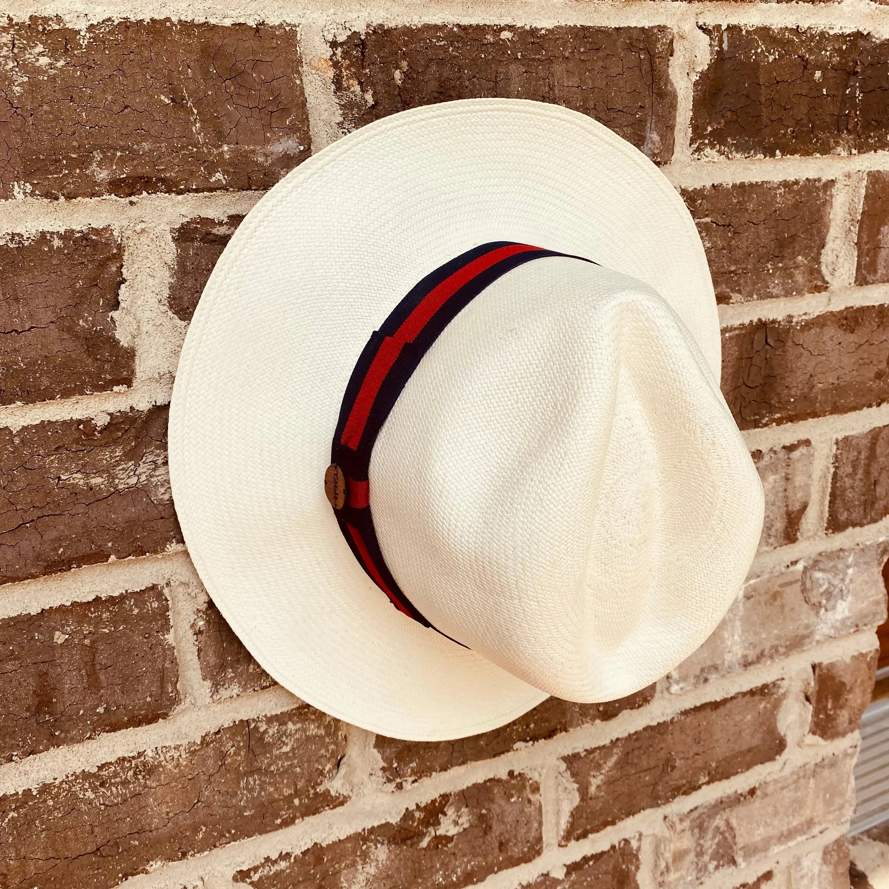 CLASSIC FEDORA STRAW HAT WITH A BLUE AND RED HAT BAND